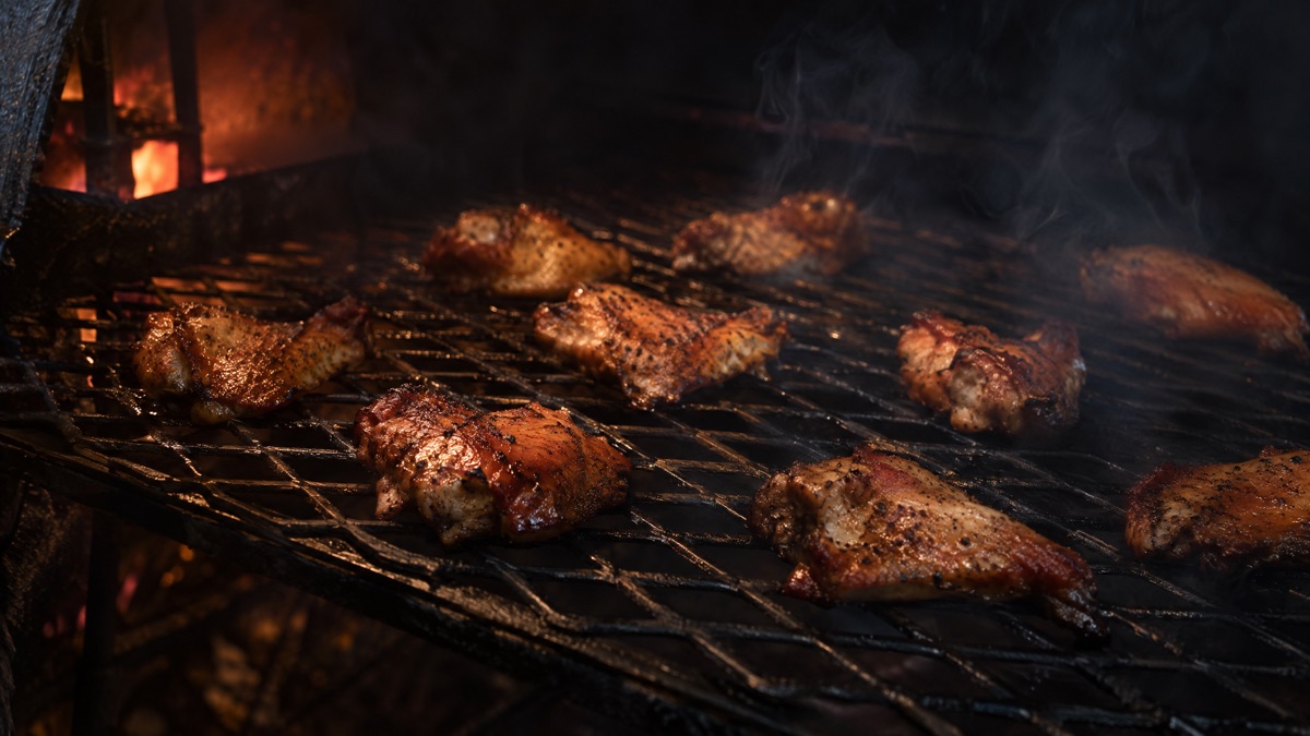 Chicken wings spaced apart on a smoker grate, none of them touching