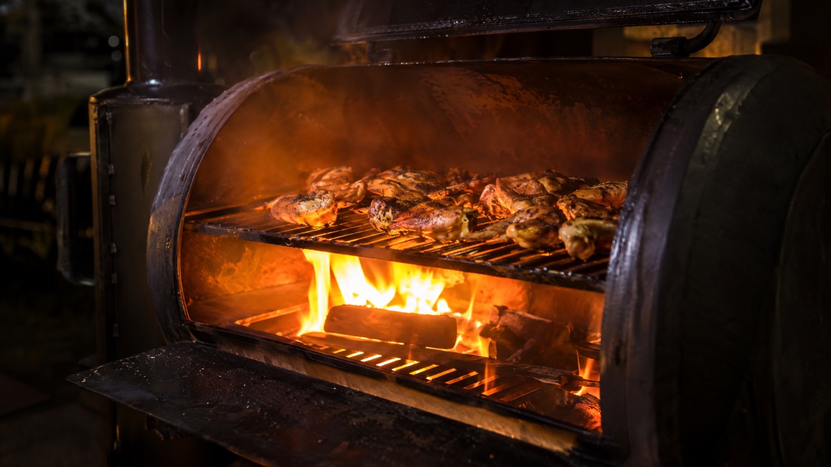 Smoker vents opened wide with the fire flaring up beneath the grate